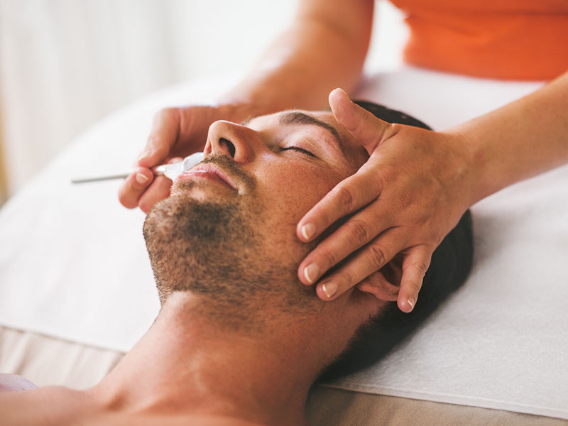 man with eyes closed receiving a facial treatment